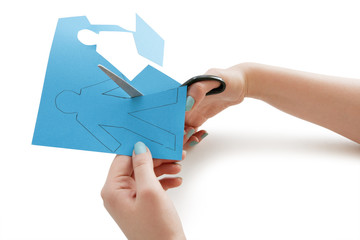 Woman's hand cutting a paper stick figure over white background