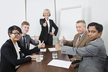 Multiethnic business people giving thumbs up in meeting