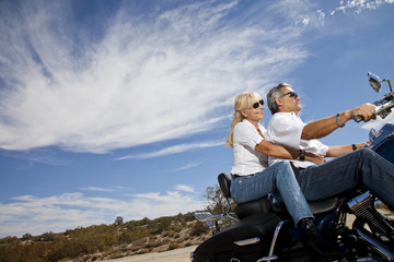 Fototapeta premium Senior couple riding motorcycle on desert road