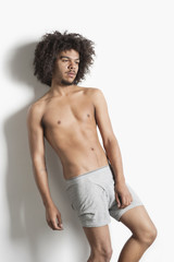 Fototapeta na wymiar Partially nude young man with curly hair posing over white background