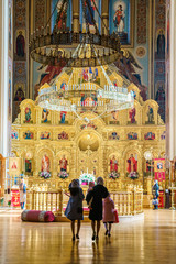Two pious women with their children have come to St. Ekaterina Orthodox Cathedral to pray and worship. Vertical inside view