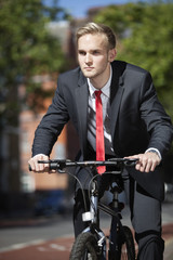 Fototapeta premium Young businessman riding bicycle on street