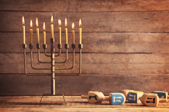 Menorah with candles for Hanukkah on table against wooden background