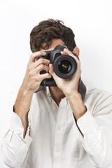 Young man taking photograph with retro style camera against white background