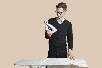 Mid adult man looking at iron over colored background