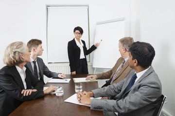 Young woman using whiteboard in business meeting