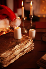 Old book and candles on wooden table