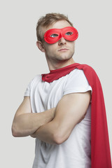 Young man in red superhero costume looking up over gray background