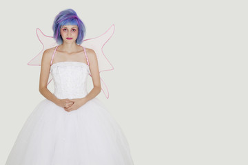 Fototapeta premium Portrait of beautiful young woman dressed as angel with dyed hair against gray background