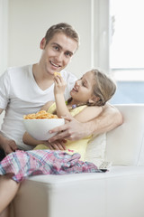 Obraz na płótnie Canvas Daughter feeding wheel shape snack pellets to her father