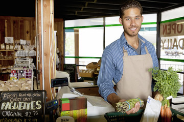 Portrait of handsome young store clerk holding vegetable in supermarket