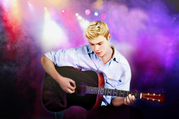 Obraz premium Young Caucasian man playing guitar in concert