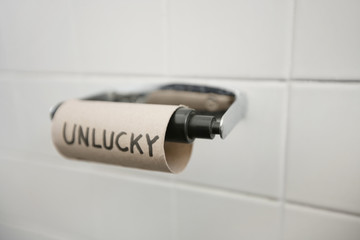 Close-up of text written on empty toilet paper roll in bathroom