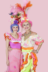Portrait of happy young and senior women in Brazilian outfits over pink background