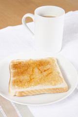 Jam on slice of bread with cup of coffee