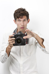 Fototapeta premium Portrait of young photographer with vintage camera gesturing against white background