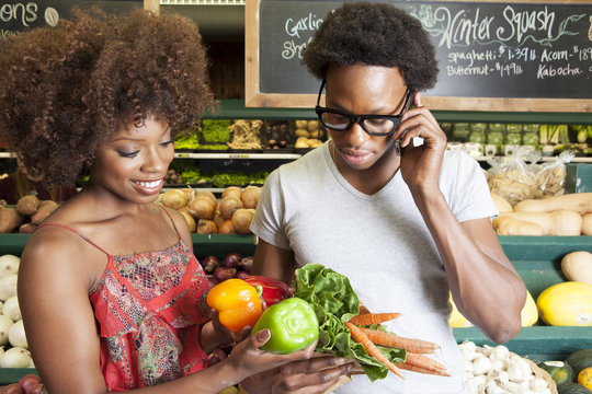 Young African American couple buying vegetables at supermarket