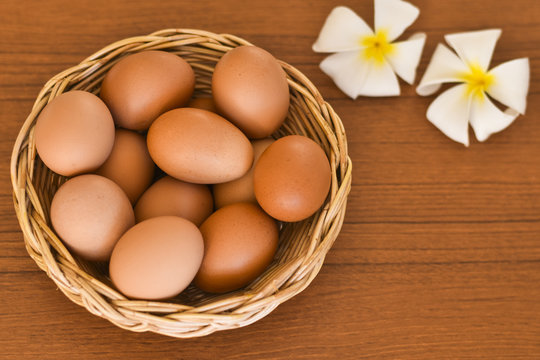 Raw organic brown eggs in wicker basket on wood table