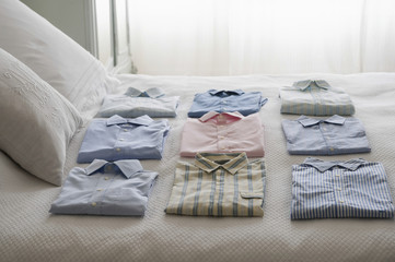 Fototapeta na wymiar Variety of clean shirts ordered on a bed