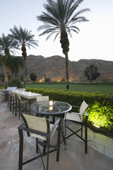 Patio chairs and tables against lawn and mountains in Palm Springs