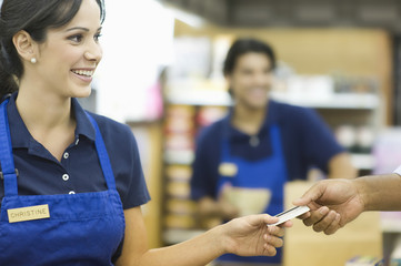 Closeup of a hand giving female employee loyalty card in supermarket