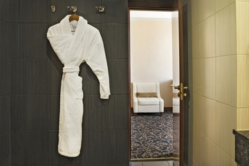 Interior of hotel room with bathrobe hanging up and the door open with a view through to the next...
