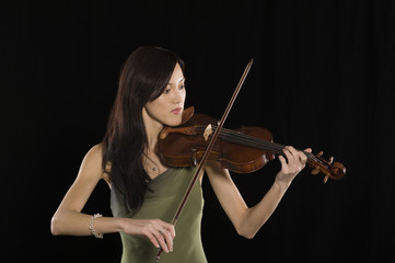 Beautiful young female playing violin isolated over black background