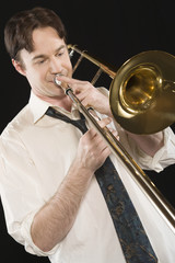 Man playing trombone isolated over black background