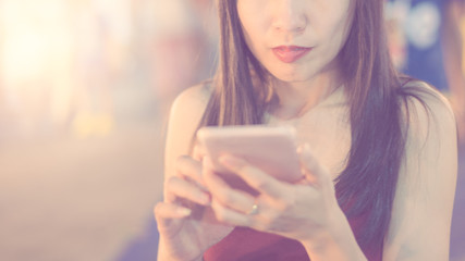 Young Asian woman, lady using smart phone, chatting with cell phone  in warm tone
