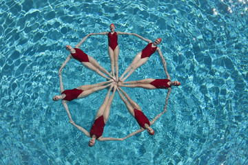 Elevated view of synchronised swimmers forming a circle in pool