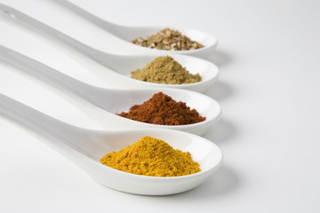 Closeup of spices in spoons isolated over white background