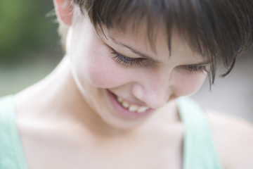 Happy shy teenage girl looking down outdoors