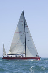 Fototapeta premium Group of crew members sitting on the side of a sailboat in the ocean