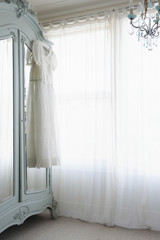 Christening gown on wardrobe at window with net curtains