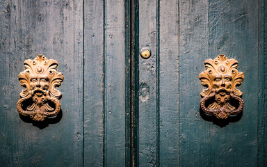 Golden door knockers of an old door in Italy.