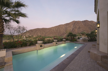 Paved poolside area of home against mountain and clear sky