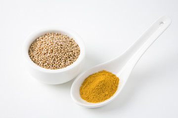 Turmeric powder and mustard seeds in utensils isolated over white background