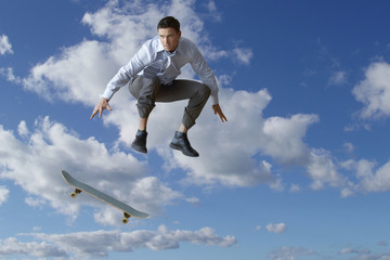 Fototapeta na wymiar Young businessman performing skateboarding trick in mid-air against cloudy sky