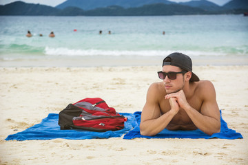 Portrait of a man in a cap and sunglasses sunbathing at Phuket, Thailand