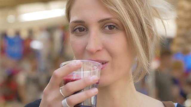 young blonde woman takes a pomegranate juice: diet, antioxidant, wellness