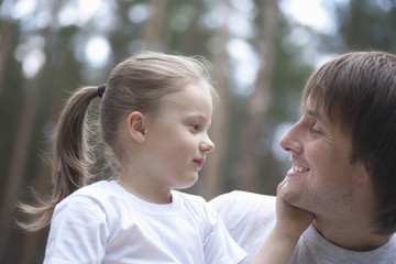 Side view of cute daughter touching father's face in park