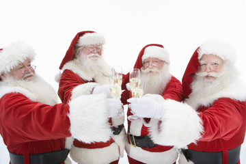 Four men dressed in Santa Claus toasting champagne isolated over white background