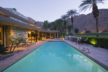 Fototapeta na wymiar View of swimming pool and illuminated modern home exterior