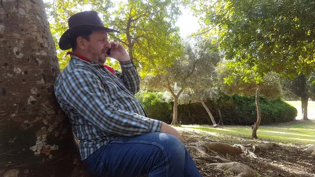 Middle aged cowboy talks on mobile phone