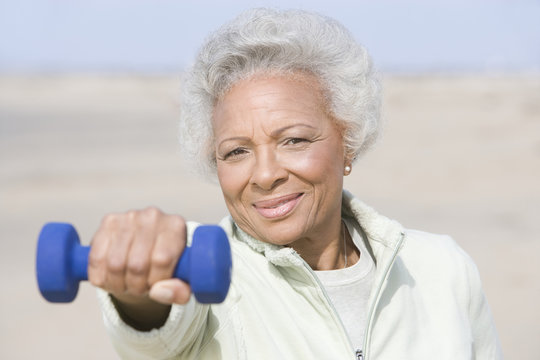 Portrait An African American Senior Woman Exercising With Dumbbells At Beach