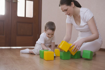 Full length of mother and son playing with green and yellow cubes at home