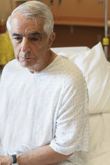 Upset elderly man sitting on hospital bed
