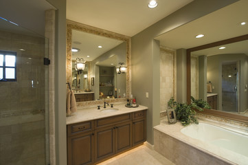 View of a modern bathroom with bathtub and square mirror at washbasin in home