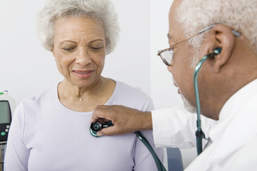 An African American senior male doctor checking patient's heartbeat using stethoscope