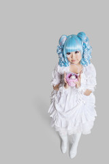 Full length portrait of cute woman in doll costume holding toy basket over gray background